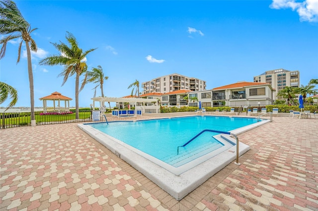 pool with a gazebo, fence, and a patio