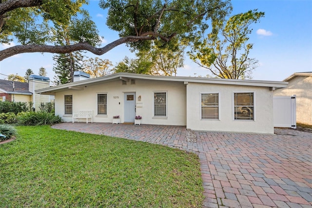 back of house featuring stucco siding, a patio, and a lawn