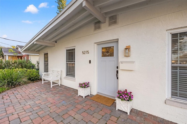 view of exterior entry featuring a patio area and stucco siding