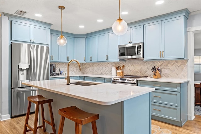 kitchen featuring stainless steel appliances, blue cabinets, light wood-style floors, and a sink