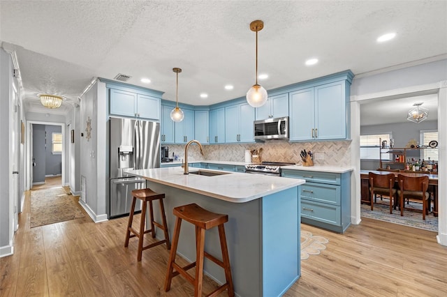 kitchen featuring visible vents, light wood finished floors, a sink, appliances with stainless steel finishes, and blue cabinets