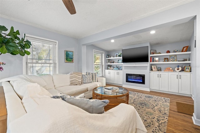 living area featuring a wealth of natural light, wood finished floors, a textured ceiling, and ceiling fan