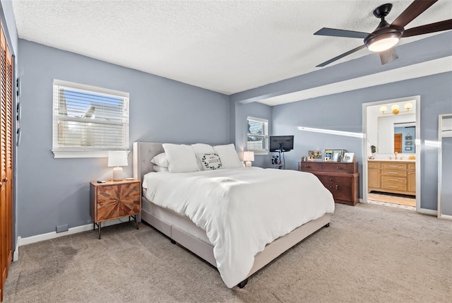 bedroom with light colored carpet, a textured ceiling, baseboards, and a sink