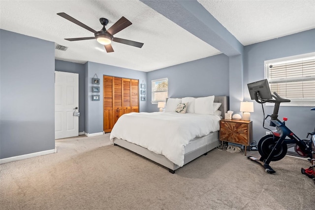 bedroom featuring visible vents, baseboards, carpet flooring, a closet, and a textured ceiling