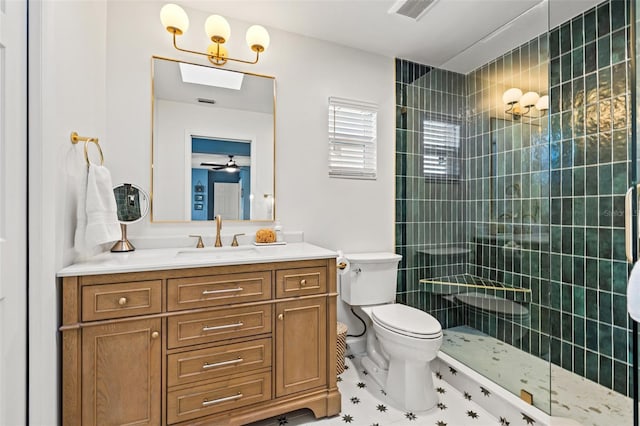 bathroom with visible vents, toilet, a tile shower, ceiling fan, and vanity