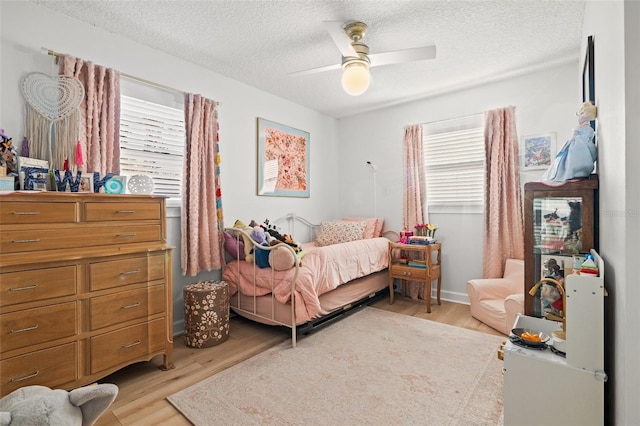 bedroom with a ceiling fan, light wood-style floors, and a textured ceiling