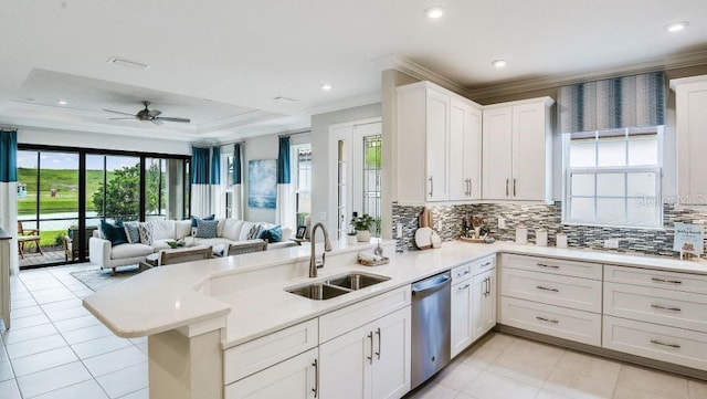 kitchen featuring open floor plan, ornamental molding, a peninsula, stainless steel dishwasher, and a sink