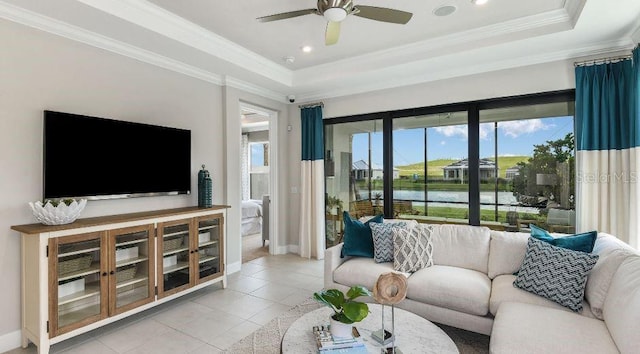 living room featuring a raised ceiling, crown molding, light tile patterned floors, baseboards, and ceiling fan