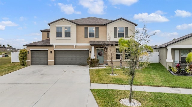 traditional-style home featuring a front yard, fence, driveway, an attached garage, and stucco siding