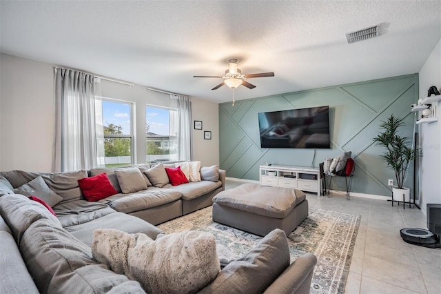 living area featuring ceiling fan, light tile patterned flooring, visible vents, and a textured ceiling