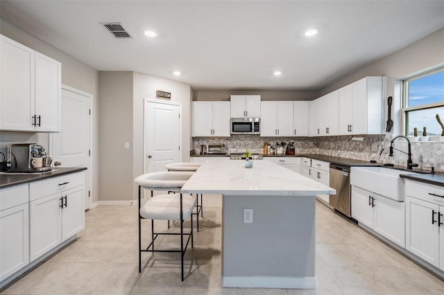 kitchen featuring a sink, a kitchen island, stainless steel appliances, a breakfast bar area, and decorative backsplash