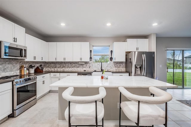 kitchen with a kitchen bar, plenty of natural light, appliances with stainless steel finishes, and a center island