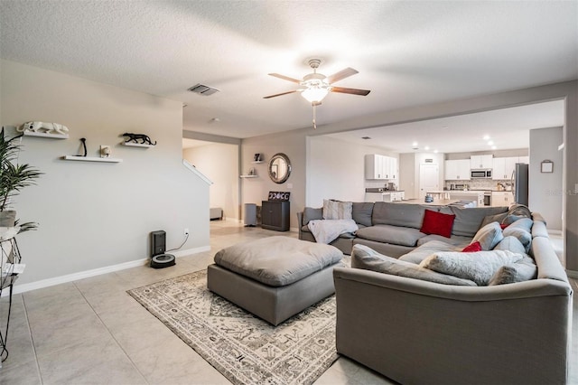 living room with visible vents, baseboards, light tile patterned floors, a textured ceiling, and a ceiling fan