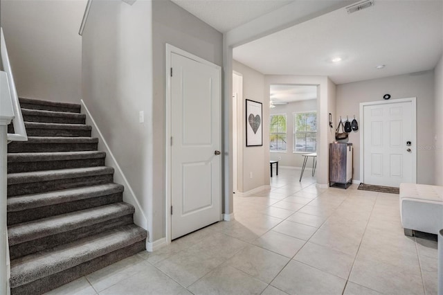 entrance foyer featuring stairs, light tile patterned flooring, baseboards, and visible vents