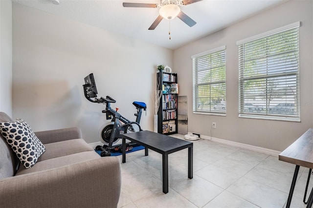 exercise room featuring light tile patterned floors, a ceiling fan, and baseboards