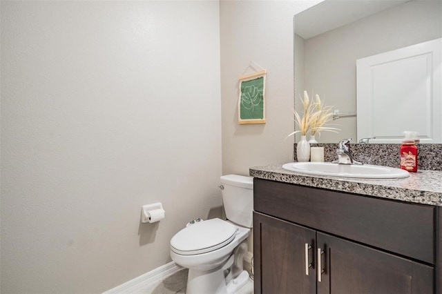 bathroom with vanity, toilet, and baseboards