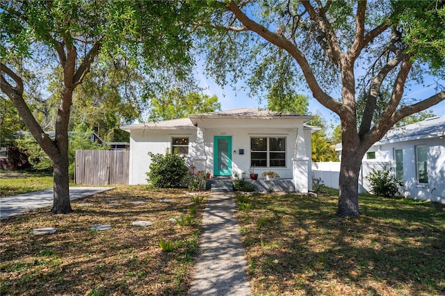 bungalow featuring stucco siding, a front lawn, and fence