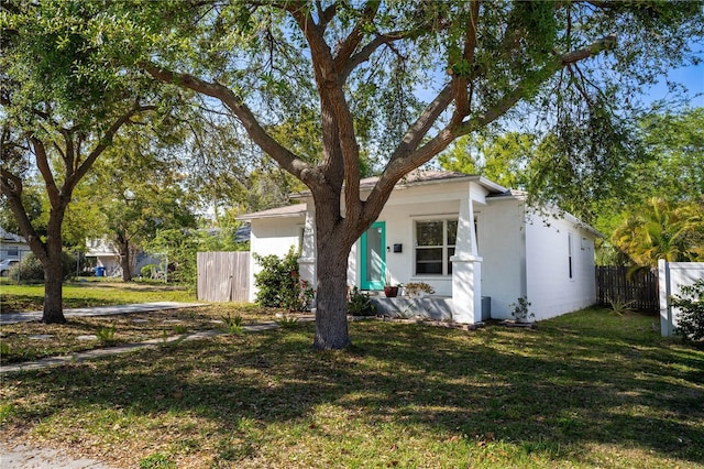 view of front of home featuring stucco siding, a front lawn, and fence