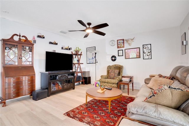 living room featuring light wood-type flooring, visible vents, and ceiling fan