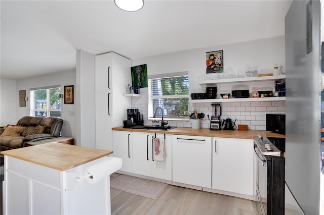 kitchen with open shelves, range with electric cooktop, wooden counters, and a sink