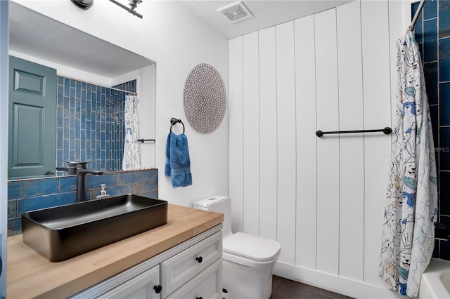 full bath featuring visible vents, shower / bath combo with shower curtain, toilet, backsplash, and vanity