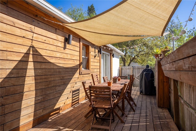 deck featuring outdoor dining space, fence, and a grill