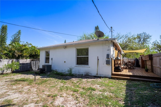 back of house featuring a deck, concrete block siding, and a fenced backyard