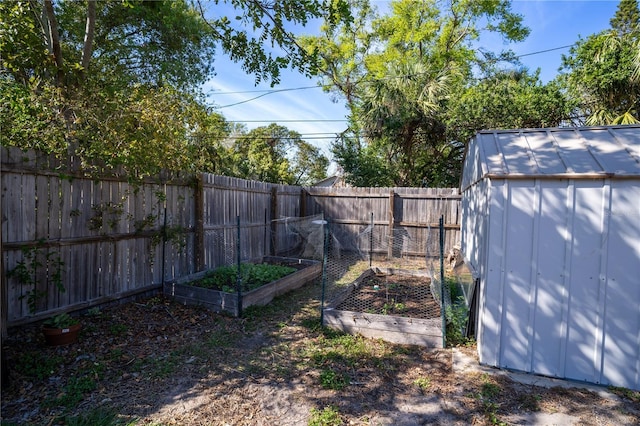 view of yard with a garden, a storage unit, an outdoor structure, and a fenced backyard