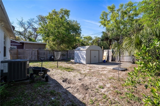 view of yard with a storage shed, an outbuilding, a fenced backyard, and central AC