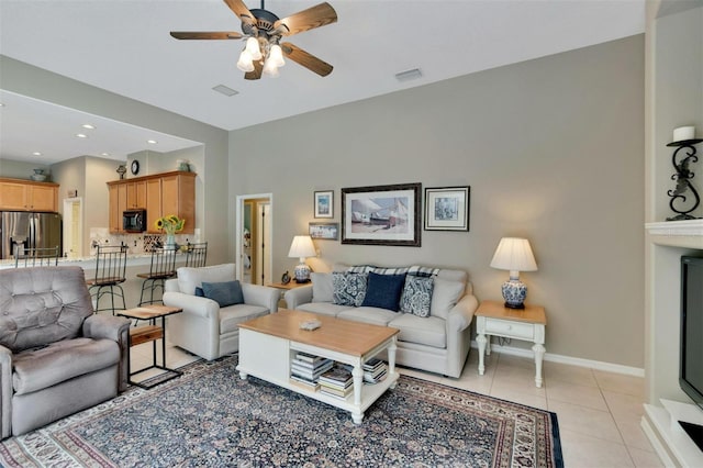 living area featuring light tile patterned floors, visible vents, ceiling fan, and baseboards