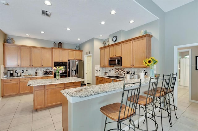 kitchen with visible vents, a center island, stainless steel appliances, a peninsula, and light stone countertops