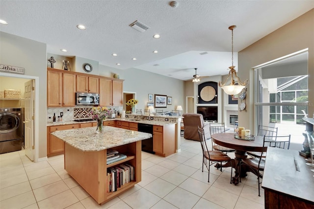 kitchen with a peninsula, washer / dryer, dishwasher, a glass covered fireplace, and stainless steel microwave