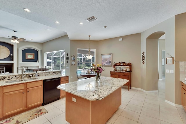 kitchen featuring visible vents, a sink, light stone counters, a center island, and dishwasher