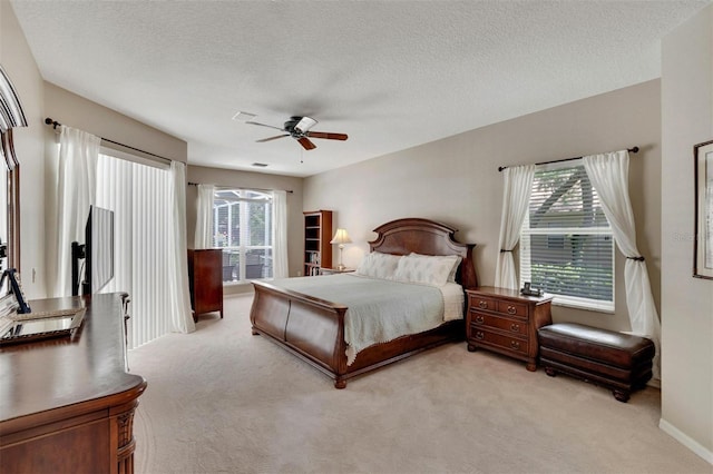 bedroom with a textured ceiling, a ceiling fan, and light carpet