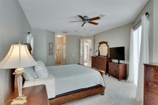 bedroom with connected bathroom, a ceiling fan, visible vents, and light carpet