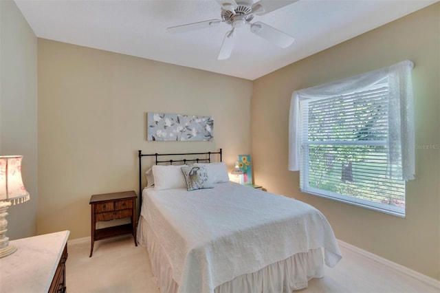 bedroom featuring light carpet, a ceiling fan, and baseboards