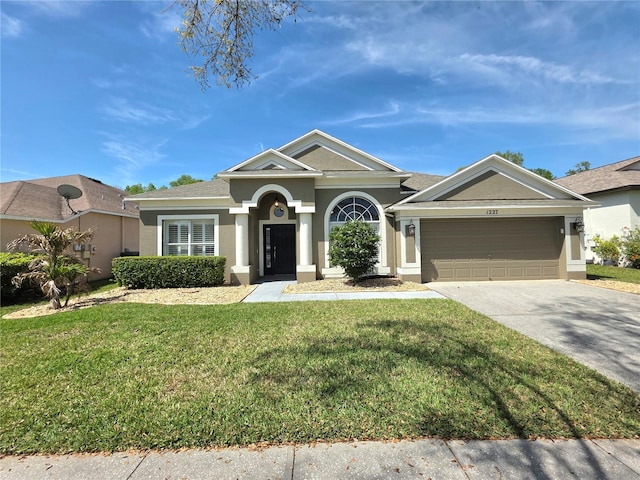 view of front facade featuring stucco siding, an attached garage, concrete driveway, and a front lawn