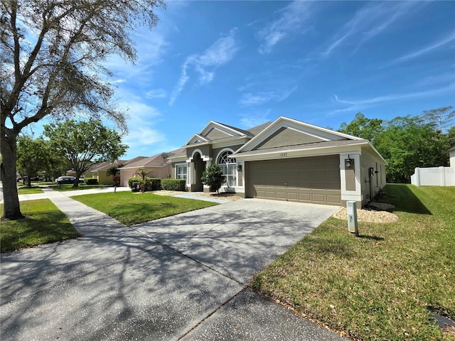 view of front of property with stucco siding, a front lawn, fence, concrete driveway, and an attached garage