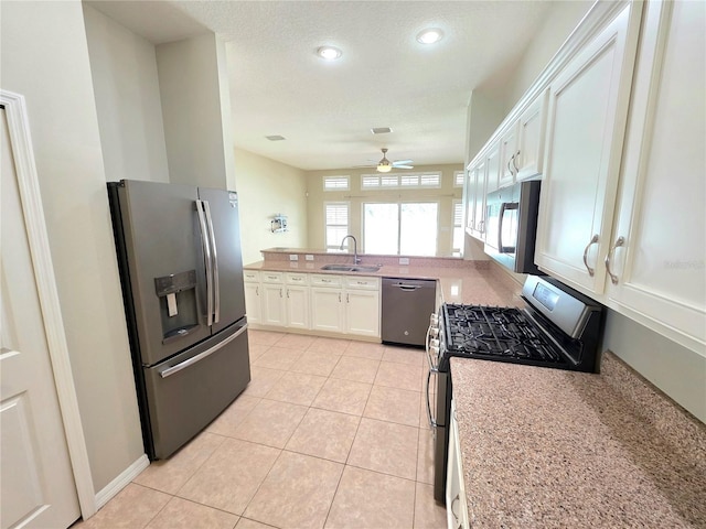 kitchen with ceiling fan, light tile patterned floors, appliances with stainless steel finishes, white cabinets, and a sink