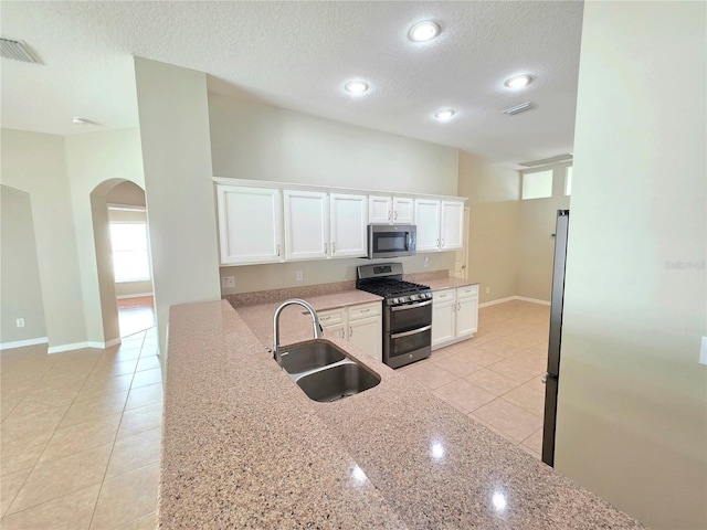 kitchen featuring visible vents, a sink, stainless steel appliances, arched walkways, and white cabinets