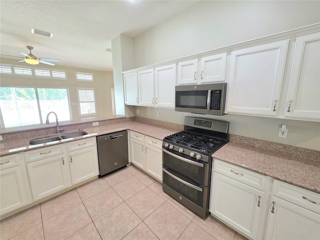 kitchen with a sink, stainless steel appliances, white cabinets, and a ceiling fan