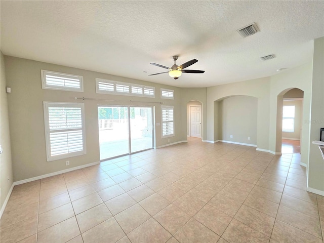 unfurnished room with light tile patterned floors, visible vents, arched walkways, and ceiling fan