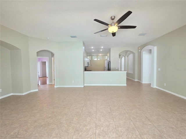 unfurnished living room featuring visible vents, arched walkways, light tile patterned floors, baseboards, and ceiling fan