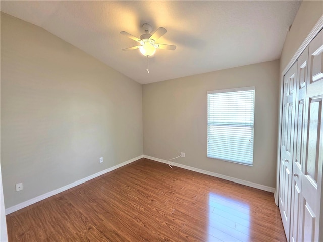 unfurnished bedroom featuring a closet, ceiling fan, baseboards, and wood finished floors