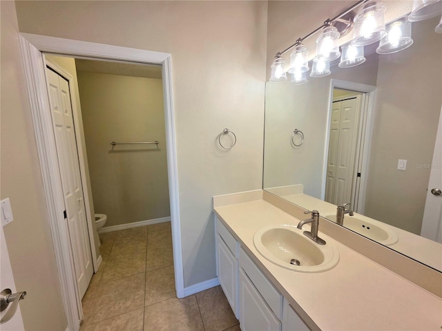 bathroom featuring tile patterned floors, toilet, a closet, baseboards, and vanity