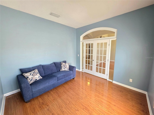 living room featuring visible vents, baseboards, wood finished floors, and french doors