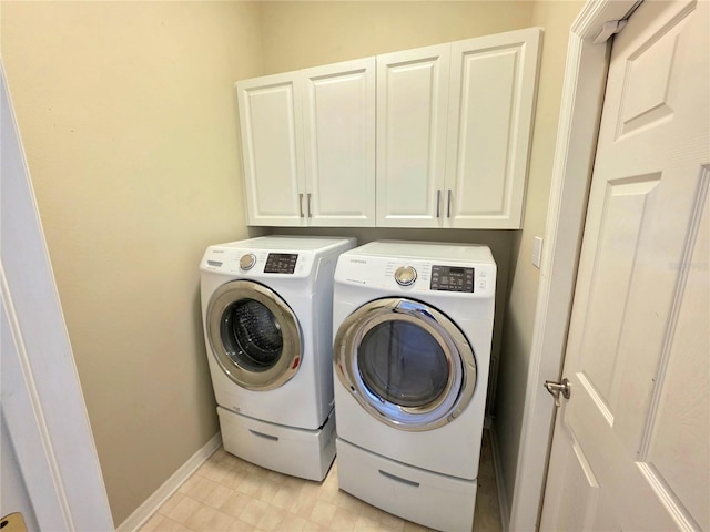 laundry room with cabinet space, washer and dryer, light floors, and baseboards