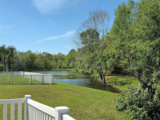 view of yard featuring a water view, a wooded view, and fence