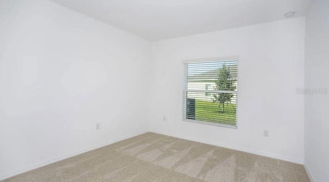 unfurnished room with light colored carpet and baseboards