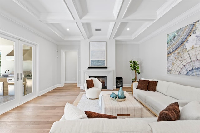 living area featuring beamed ceiling, visible vents, light wood-style flooring, french doors, and a fireplace